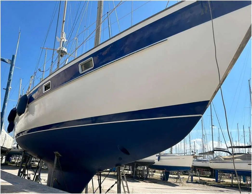 Hallberg Rassy 49 — Voilier blanc et bleu sur ber, vu en contre-plongée dans un chantier naval.