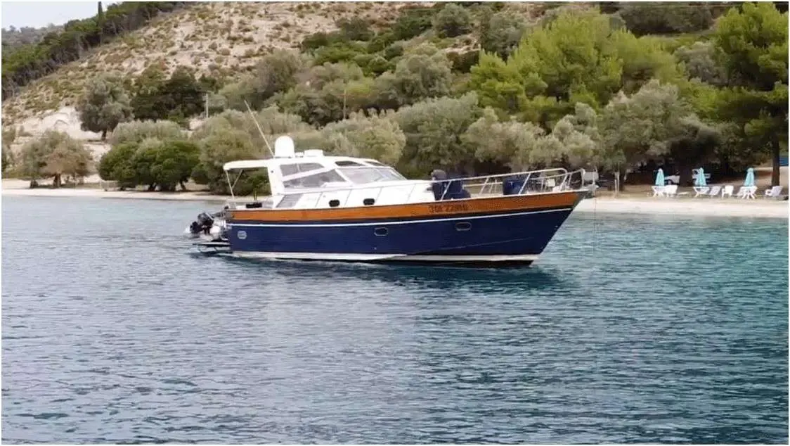 Apreamare 12 — Bateau à moteur bleu et blanc photographié au mouillage près d'une plage.