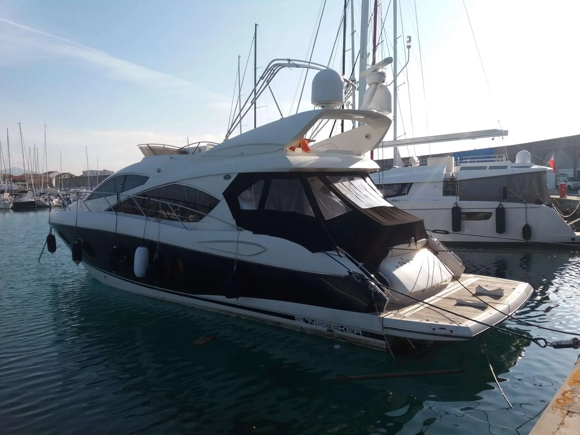 Sunseeker Manhattan 52 — Vedette à moteur blanche amarrée dans une marina, vue de trois quarts arrière.