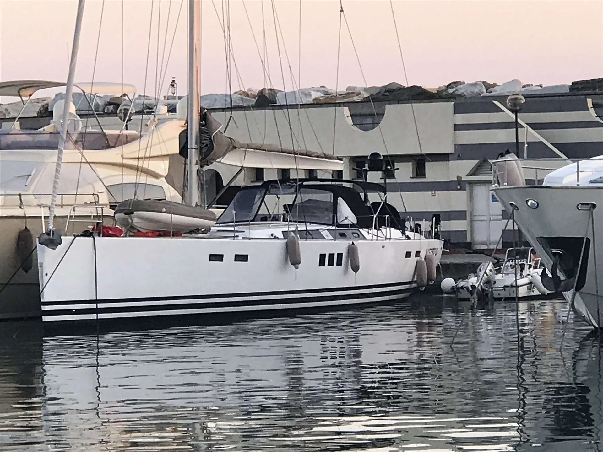 Hanse 630 — Voilier blanc amarré dans un port, vu de profil bâbord parmi d'autres bateaux.