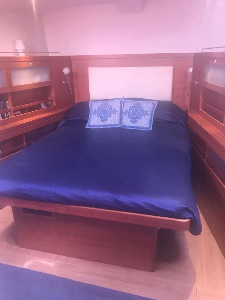 Hanse 630 — Cabine avec lit double, rangements latéraux et deux oreillers décoratifs.