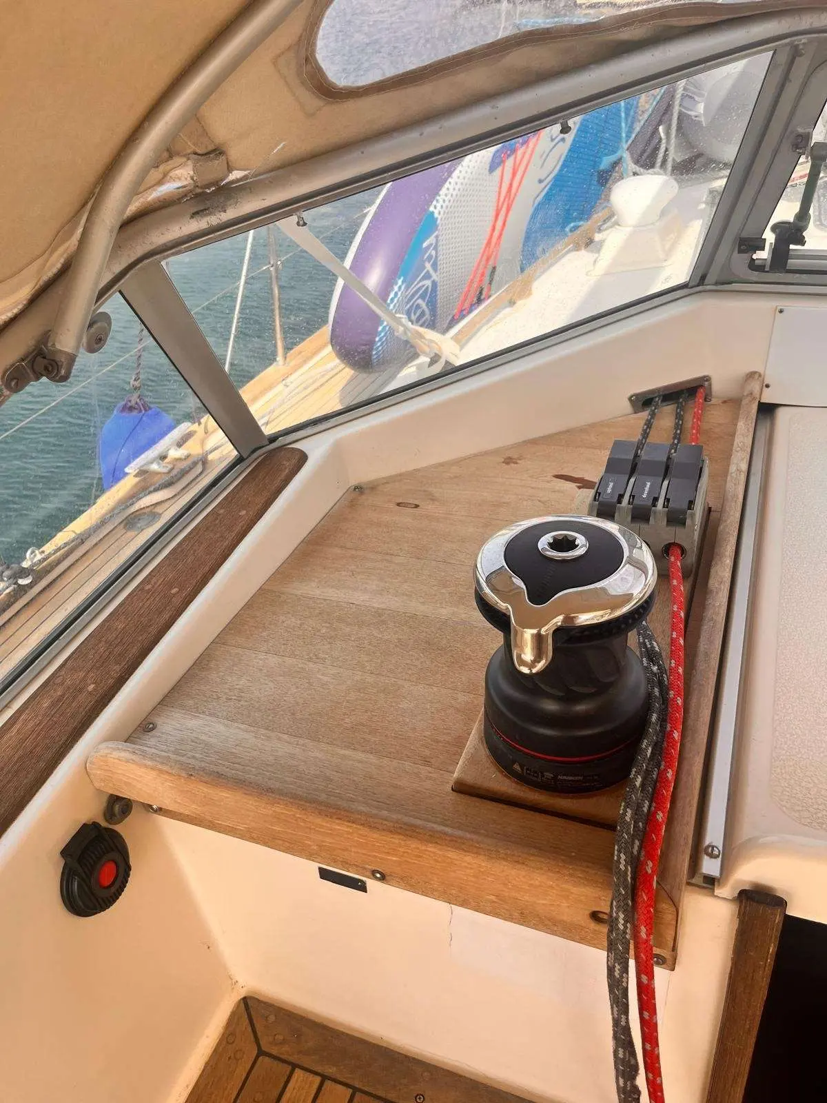 Hallberg Rassy 36 — Vue rapprochée du cockpit avec winch, manettes et plancher en bois.