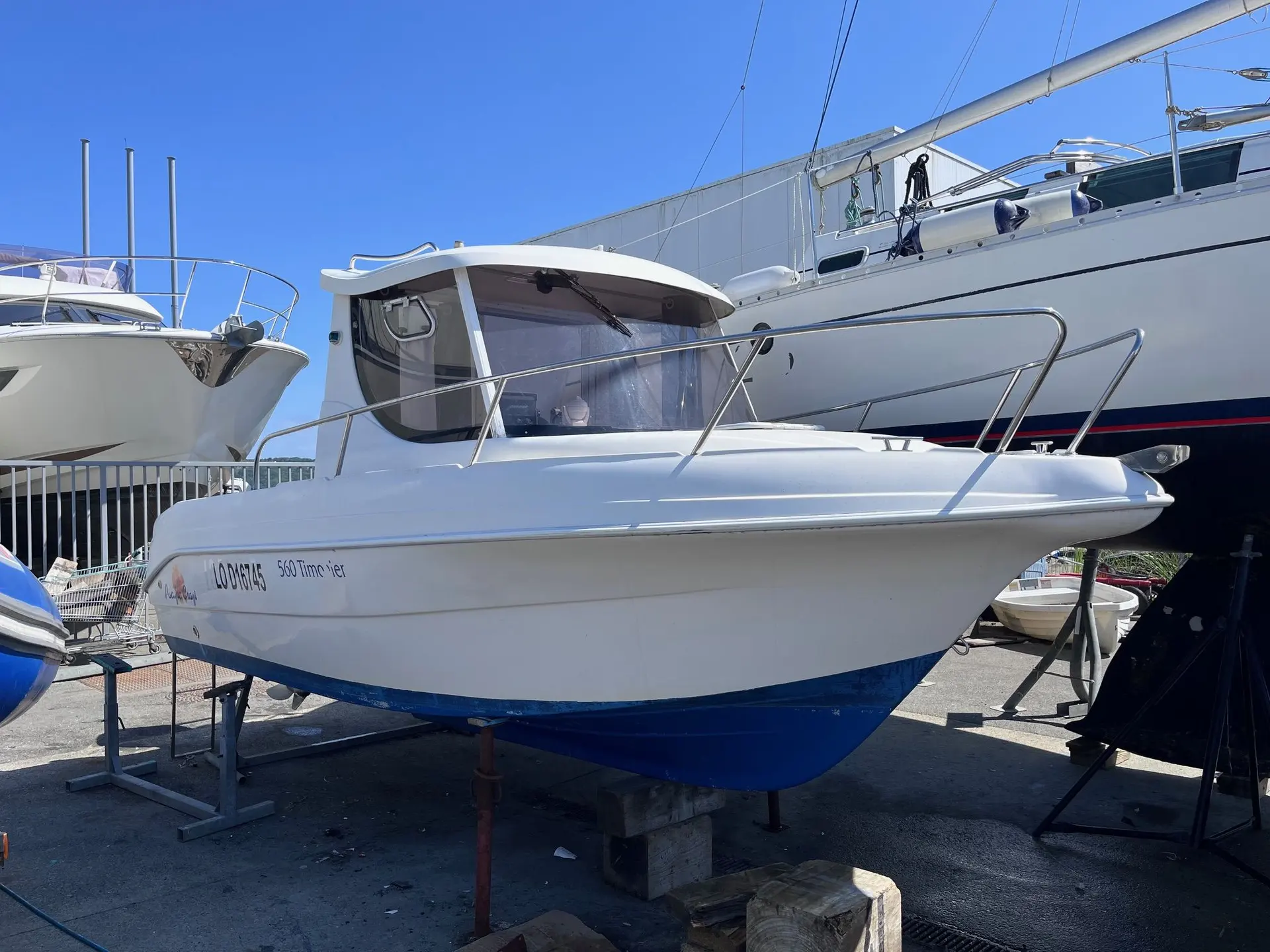 Pacific Craft 560 Pilothouse — Bateau à moteur blanc à cabine, présenté sur berceau dans un chantier naval.
