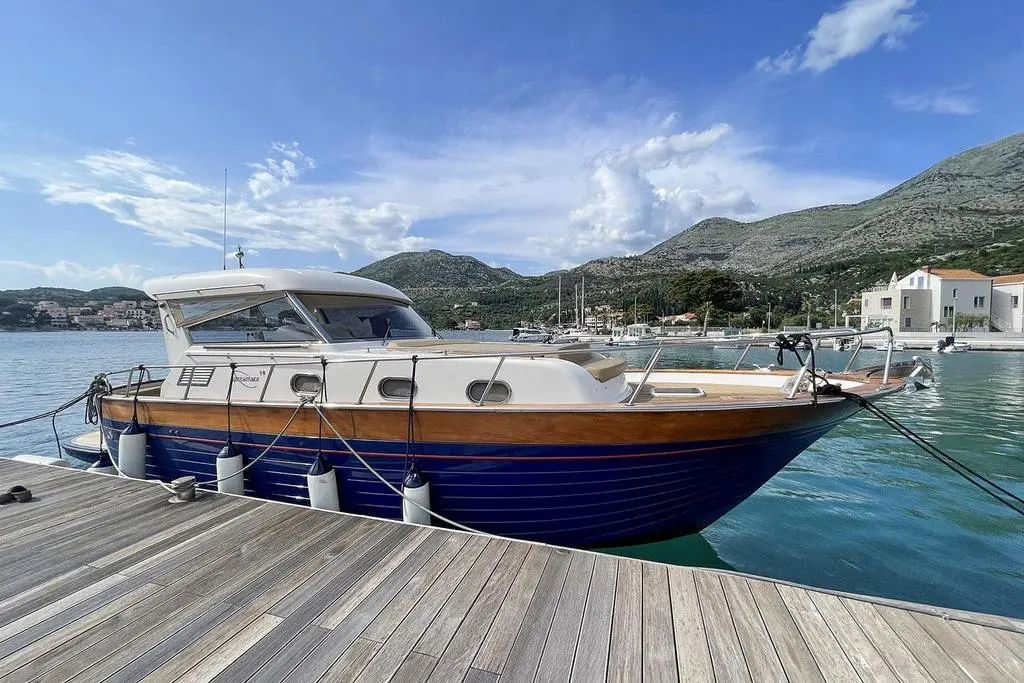 Apreamare 38 Open — Bateau à cabine amarré de trois quarts dans un port, devant un paysage montagneux.