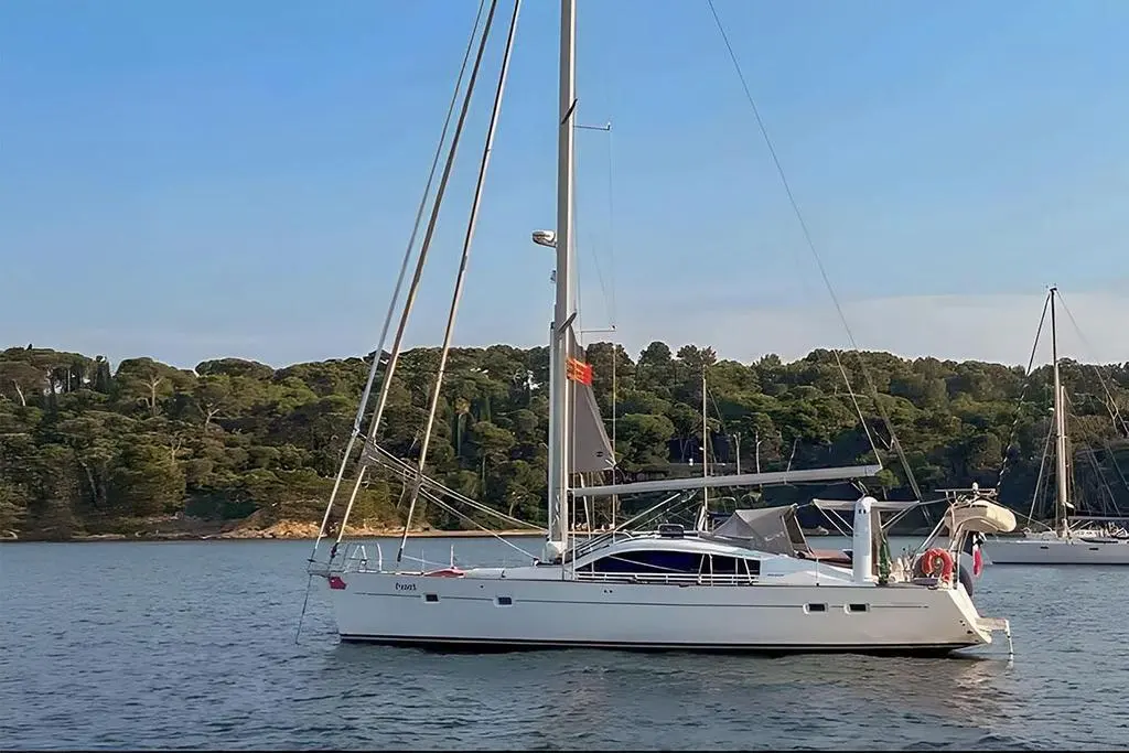 Wauquiez Pilot Saloon 47 — Voilier blanc amarré dans une baie boisée, photographié de profil.