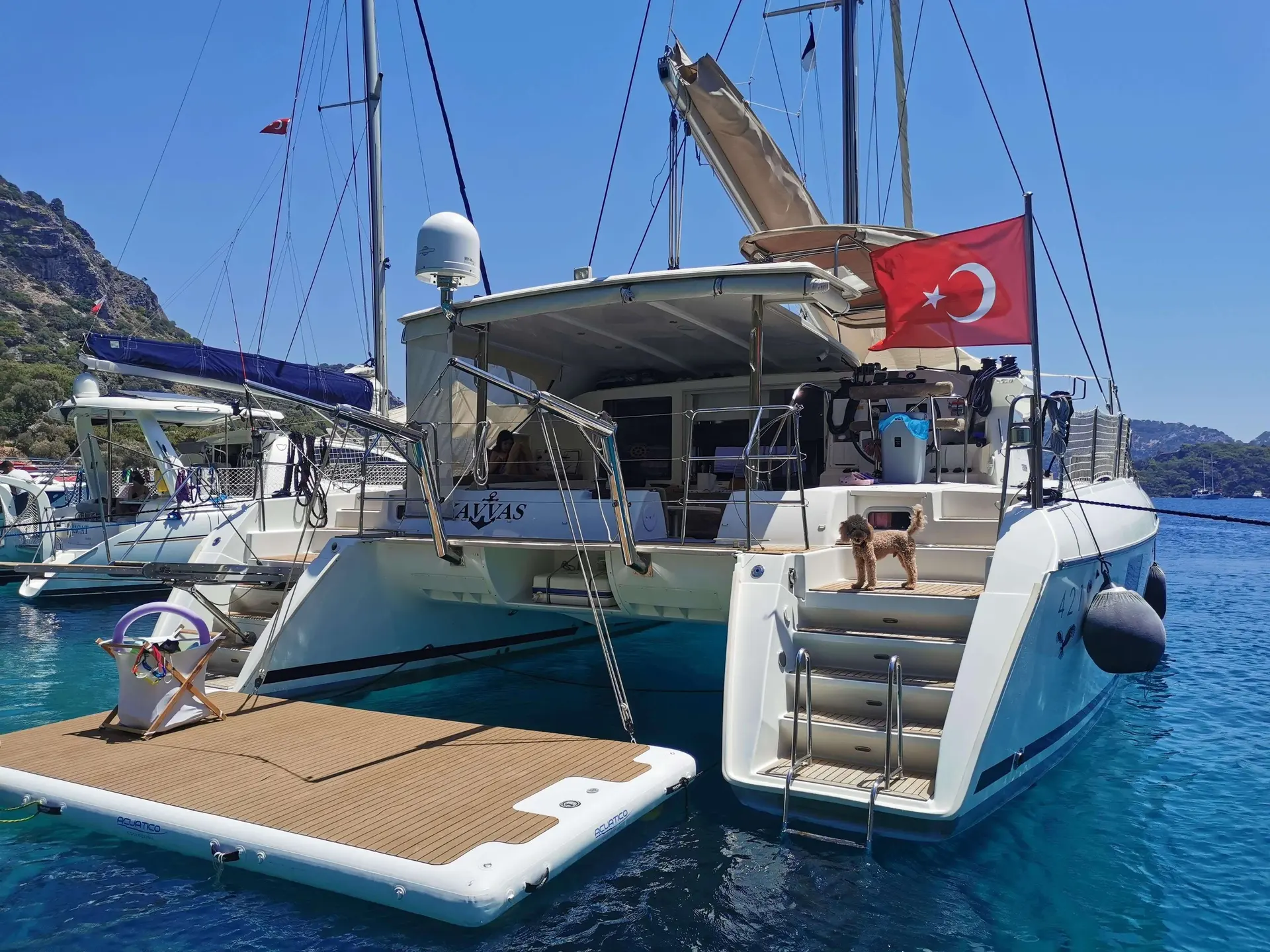 Lagoon 421 — Catamaran vu de l’arrière dans une marina, avec une annexe et un chien à bord.