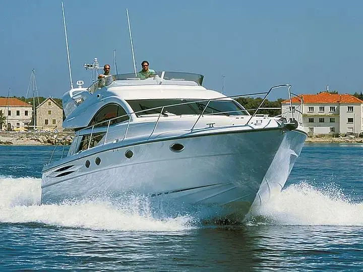 Fairline Phantom 50 — Bateau à moteur vu de trois quarts avant, naviguant à vive allure près d’une côte.