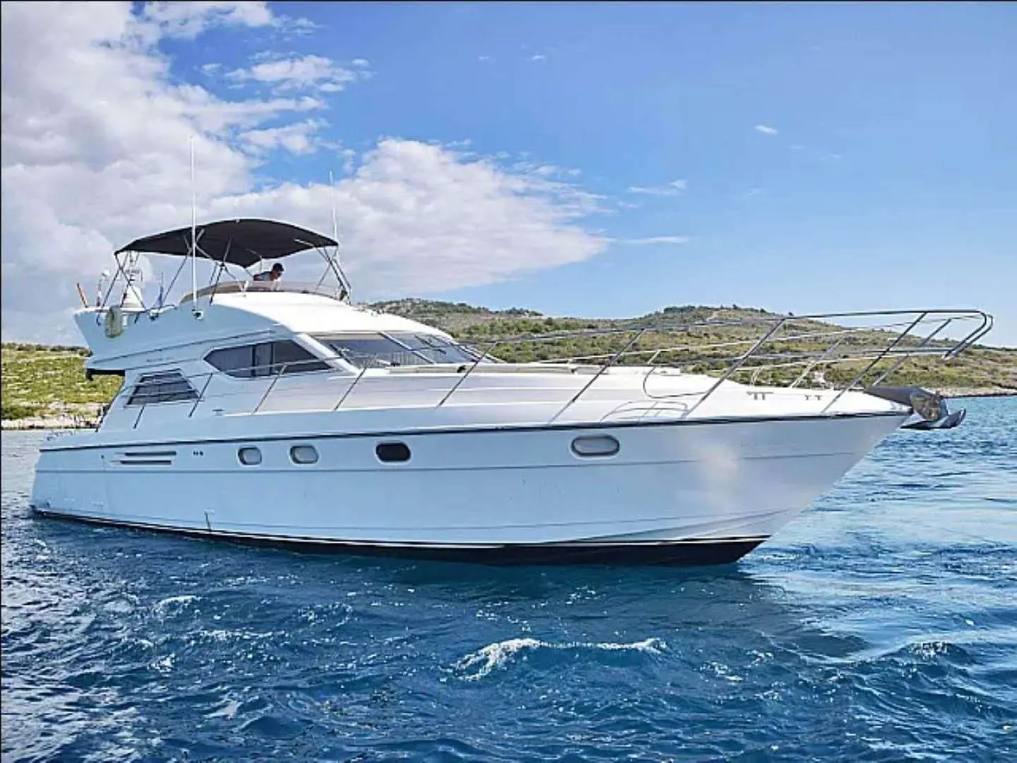 Princess 480 — Bateau à moteur blanc vu de profil sur une mer agitée, près d’une côte.
