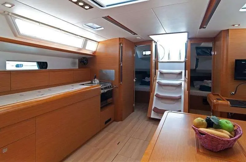 Jeanneau Sun Odyssey 469 — Vue intérieure montrant la cuisine, le carré et l'escalier vers les cabines.