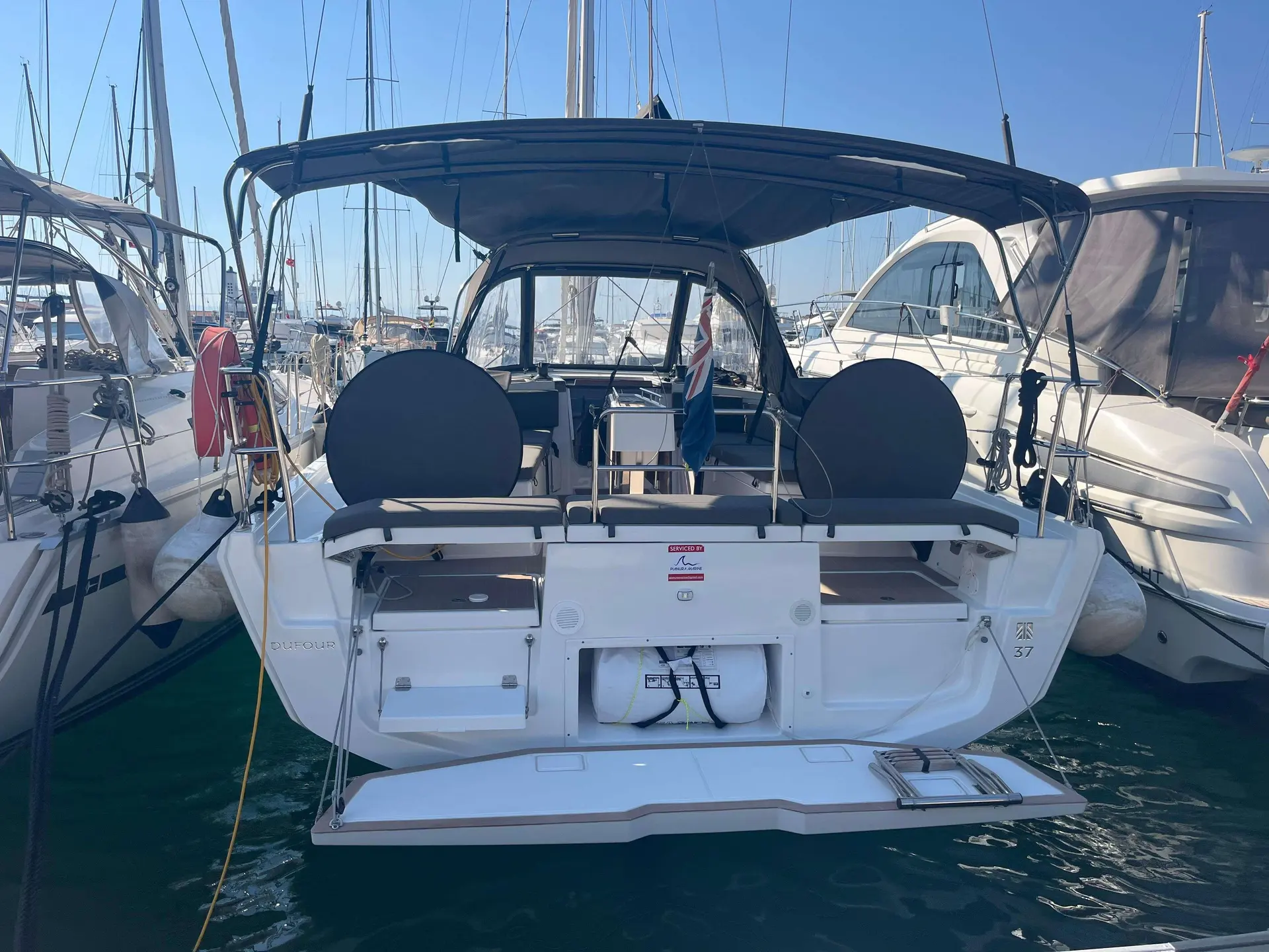 Dufour Gib Sea 37 — Vue arrière d’un voilier amarré, avec cockpit couvert et double barre.