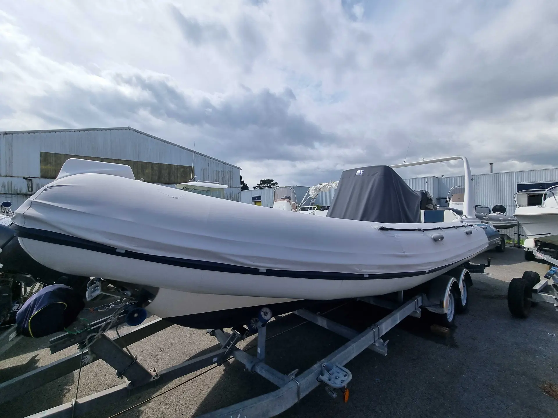 Valiant 750 — Semi-rigide blanc bâché, présenté sur sa remorque dans un parc nautique.