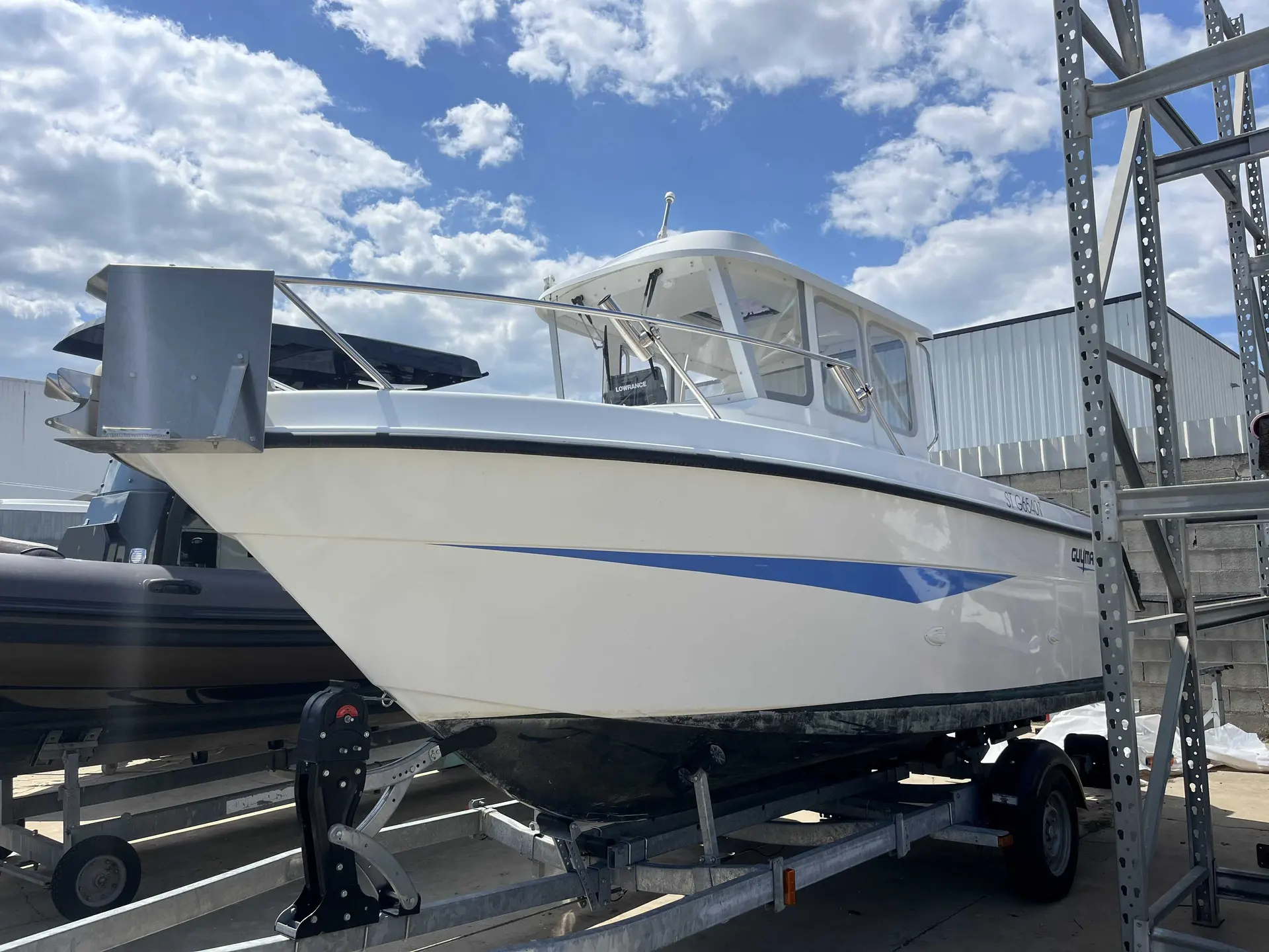 Guymarine Antioche 600 Chalutier — Bateau à cabine blanche et bande bleue présenté sur sa remorque dans un chantier.