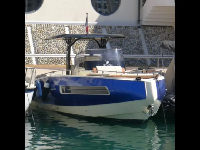 Invictus 280 TT — Bateau à moteur bleu et blanc amarré dans un port, vu de trois quarts arrière.