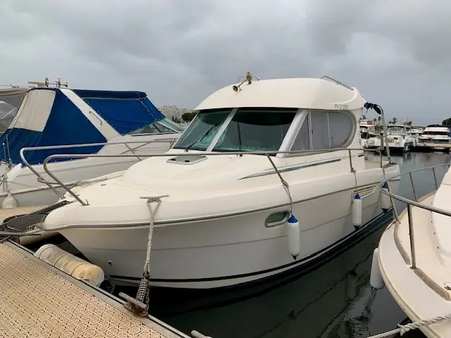 Jeanneau Merry Fisher 805 — Bateau à moteur blanc amarré dans une marina, vu de trois quarts avant.