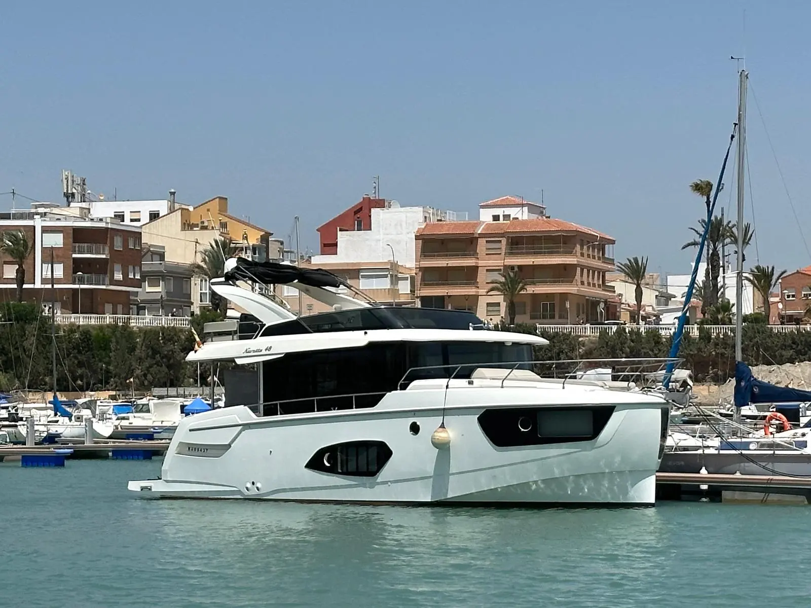 Absolute Navetta 48 — Yacht à moteur blanc amarré dans une marina, vu de trois quarts.