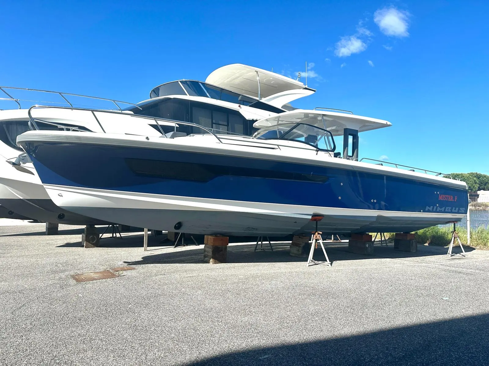 Nimbus T11 — Bateau à moteur blanc et bleu photographié à terre, sur supports, sous un ciel dégagé.