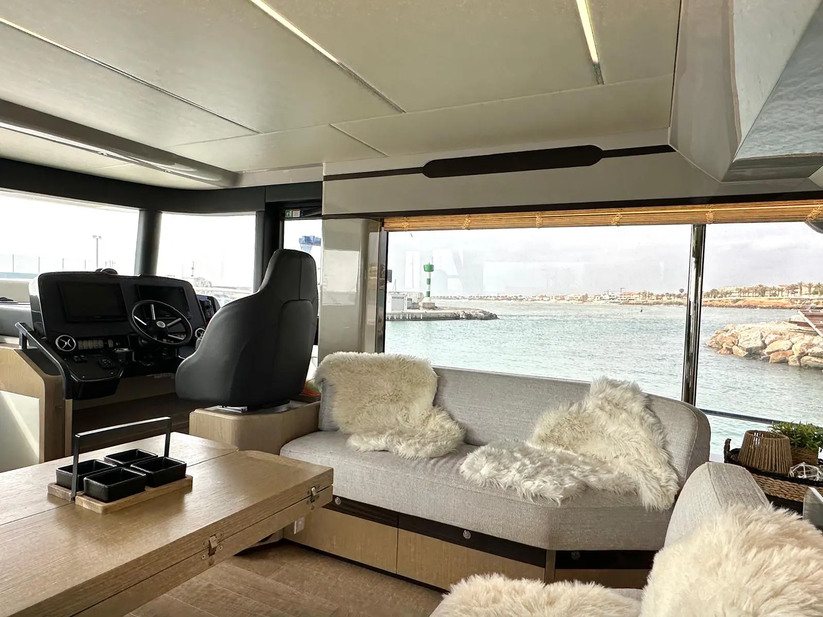 Absolute Navetta 48 — Salon intérieur avec poste de pilotage et vue sur le port.