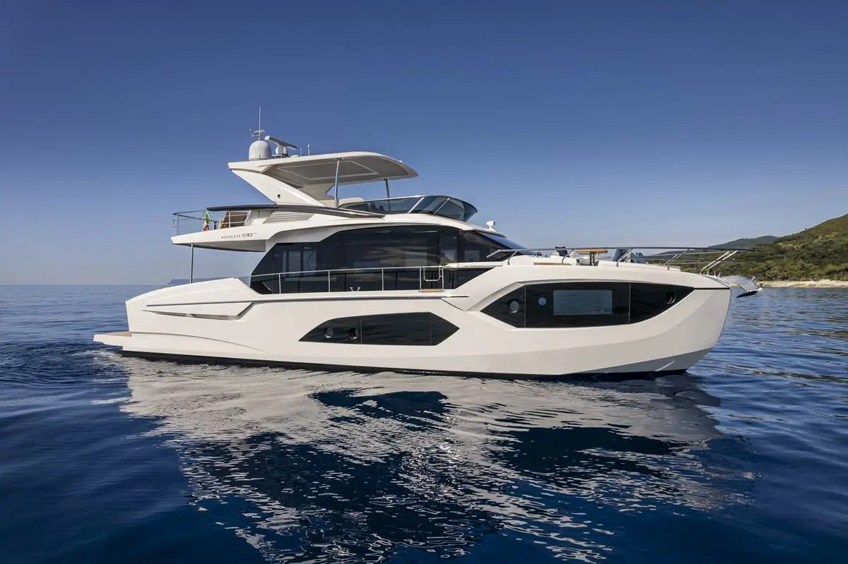 Absolute 60 Fly — Bateau à moteur blanc photographié de profil sur l’eau, près d’une côte rocheuse.