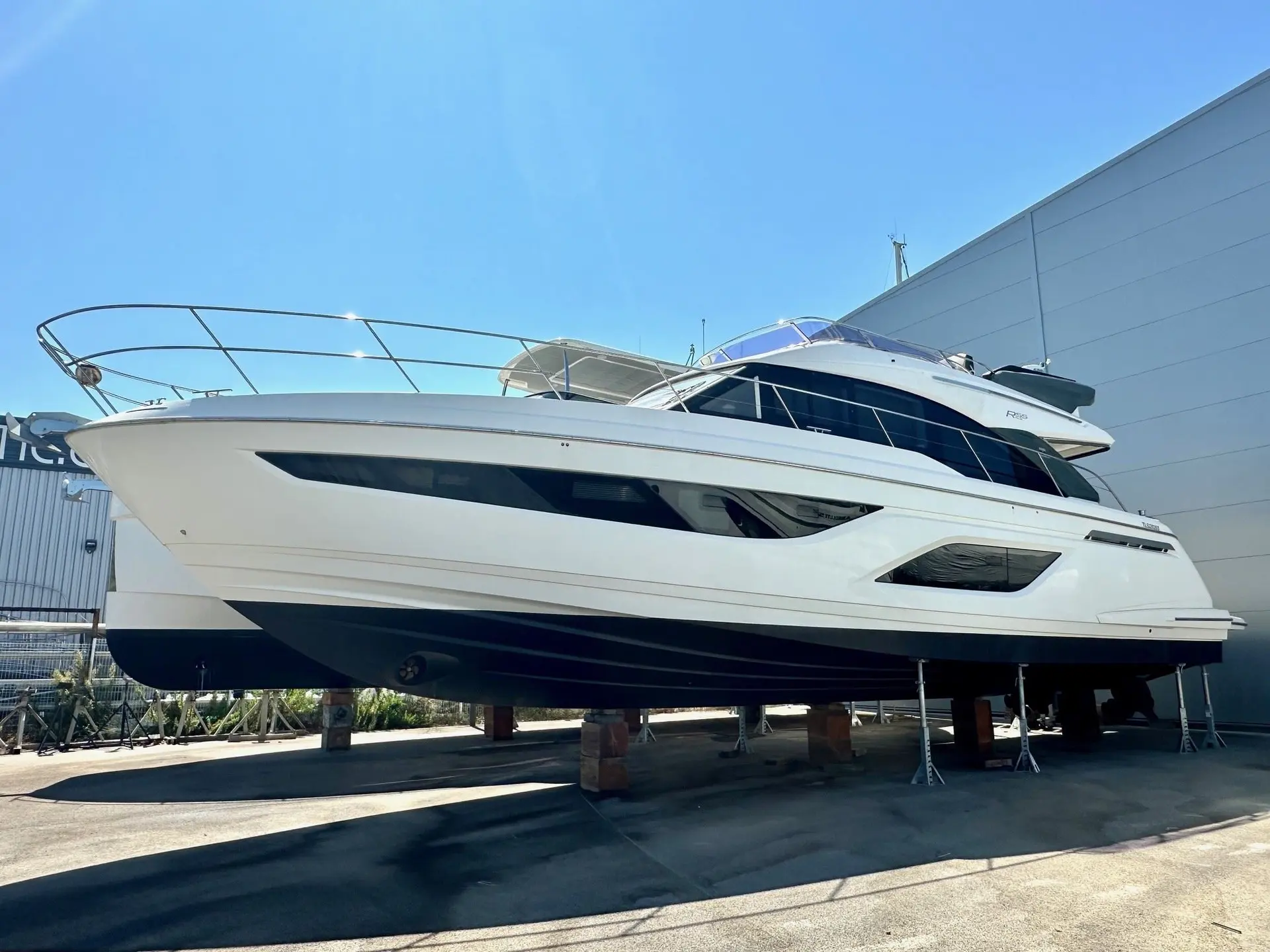 Bavaria R55 Fly — Bateau à moteur blanc vu de trois quarts, stationné à terre sur bers.