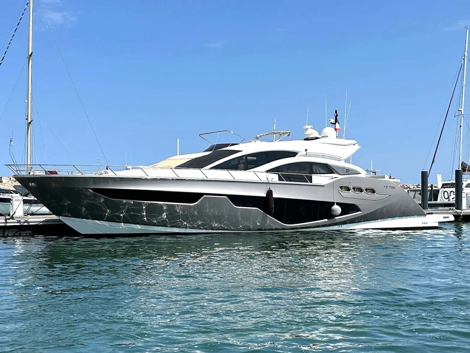 Sessa Marine C68 — Bateau à moteur vu de profil, amarré dans une marina par temps ensoleillé.