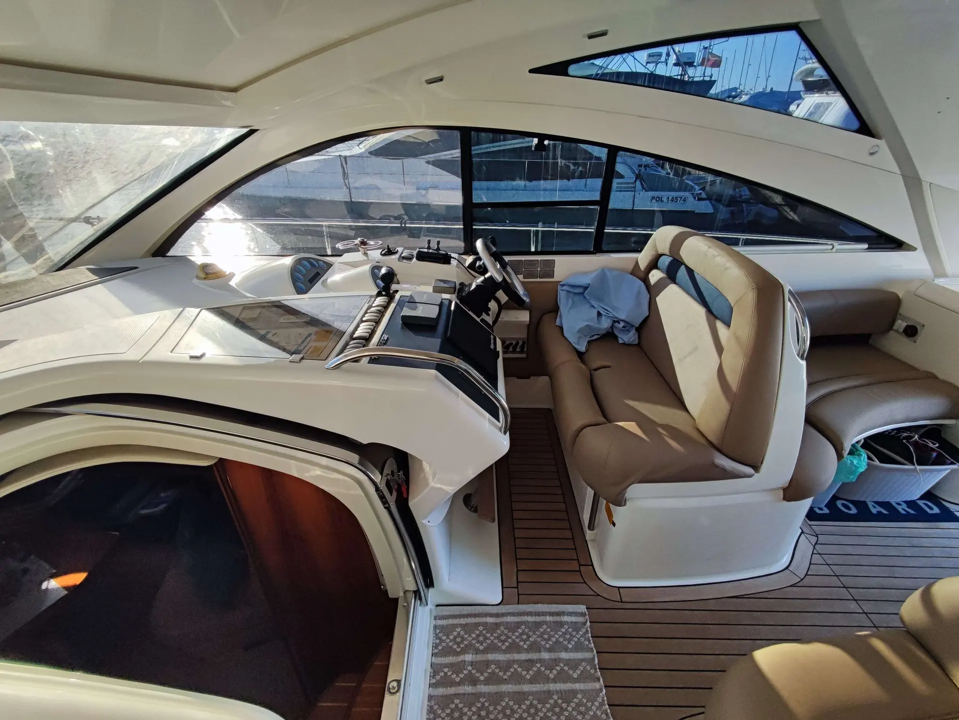 Fairline Targa 52 — Poste de pilotage intérieur et salon d’un bateau, vus depuis l’accès arrière.