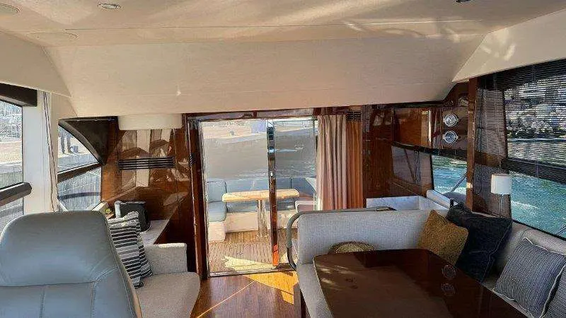 Princess 49 — Vue du salon intérieur avec banquette, fauteuils et accès à la plage arrière.