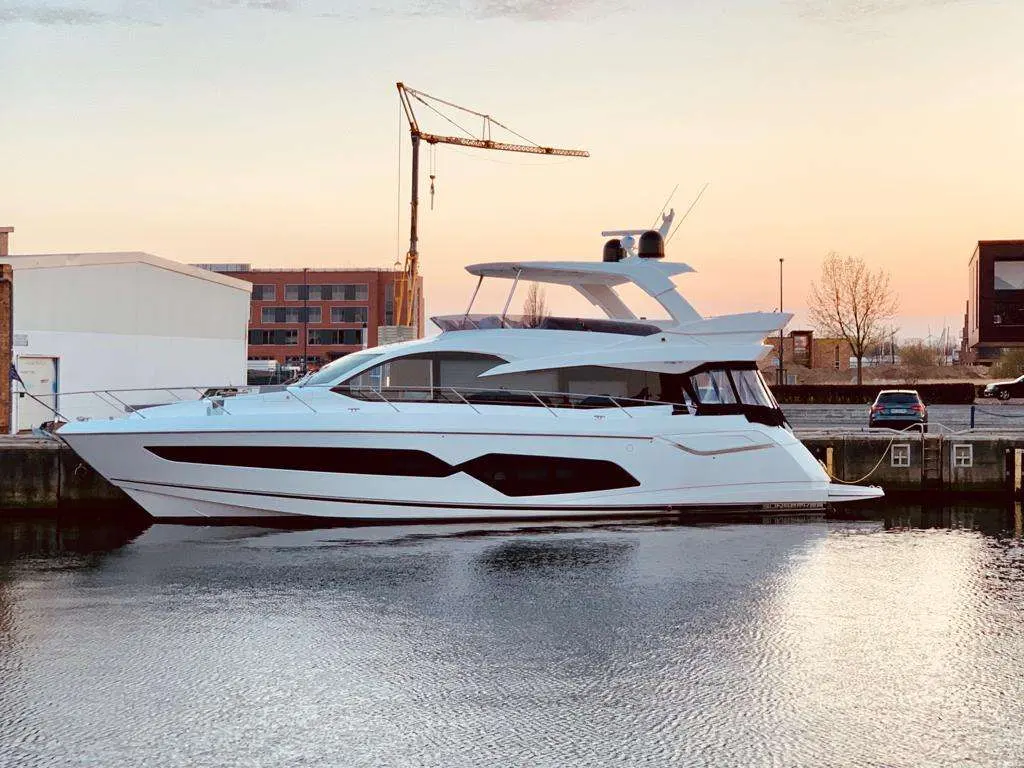 Sunseeker Manhattan 66 — Bateau à moteur blanc vu de profil dans un bassin au coucher du soleil.