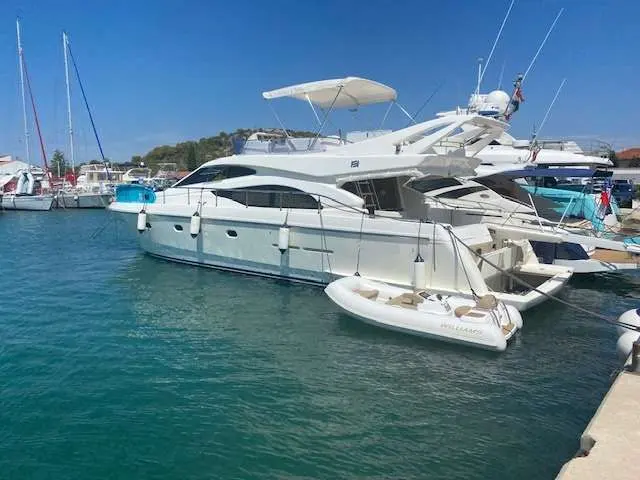 Ferretti 530 — Bateau à moteur blanc amarré dans une marina, avec une annexe à proximité.