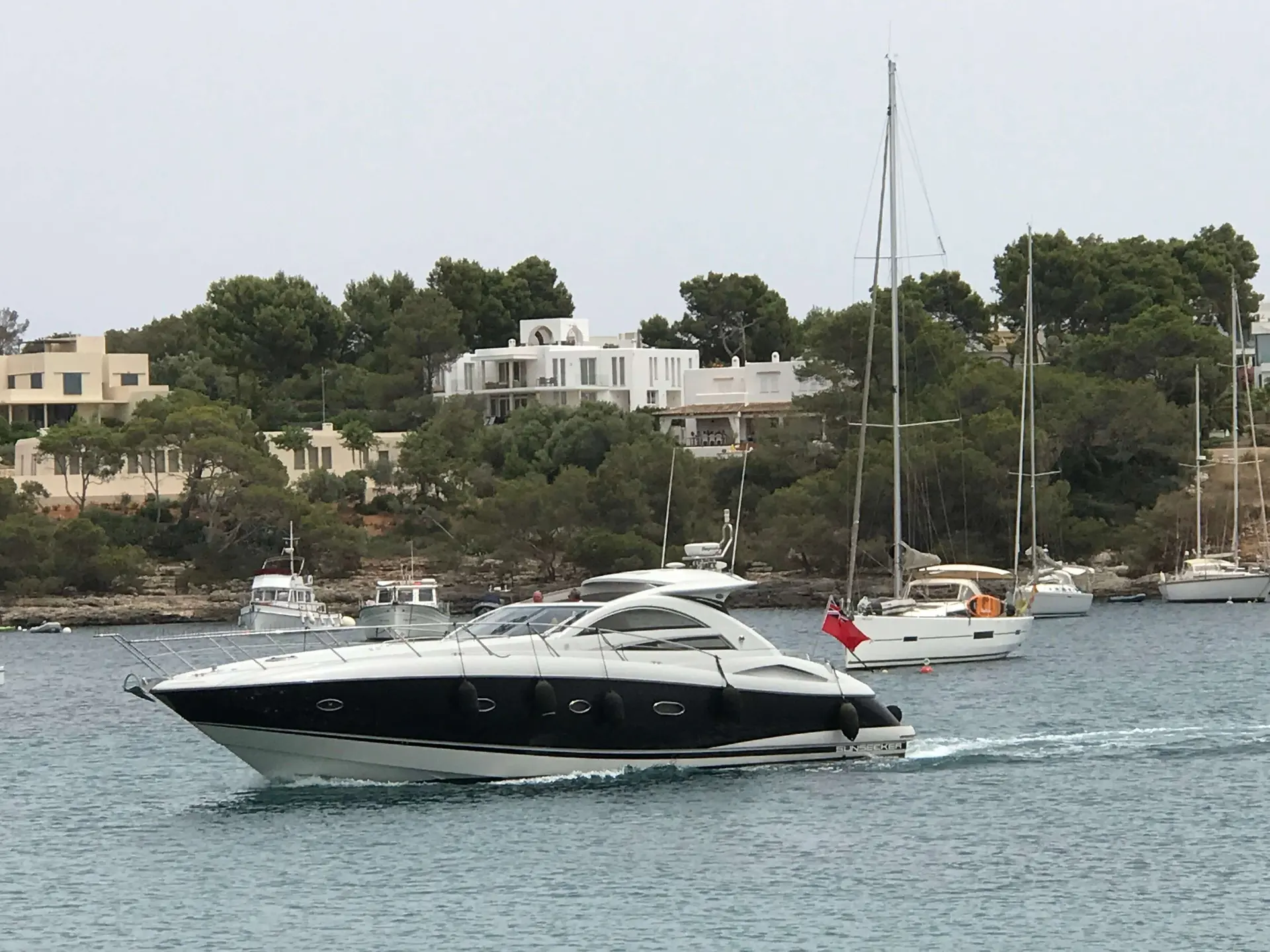 Sunseeker Portofino 53 — Bateau à moteur noir et blanc naviguant dans une baie, vu de profil.