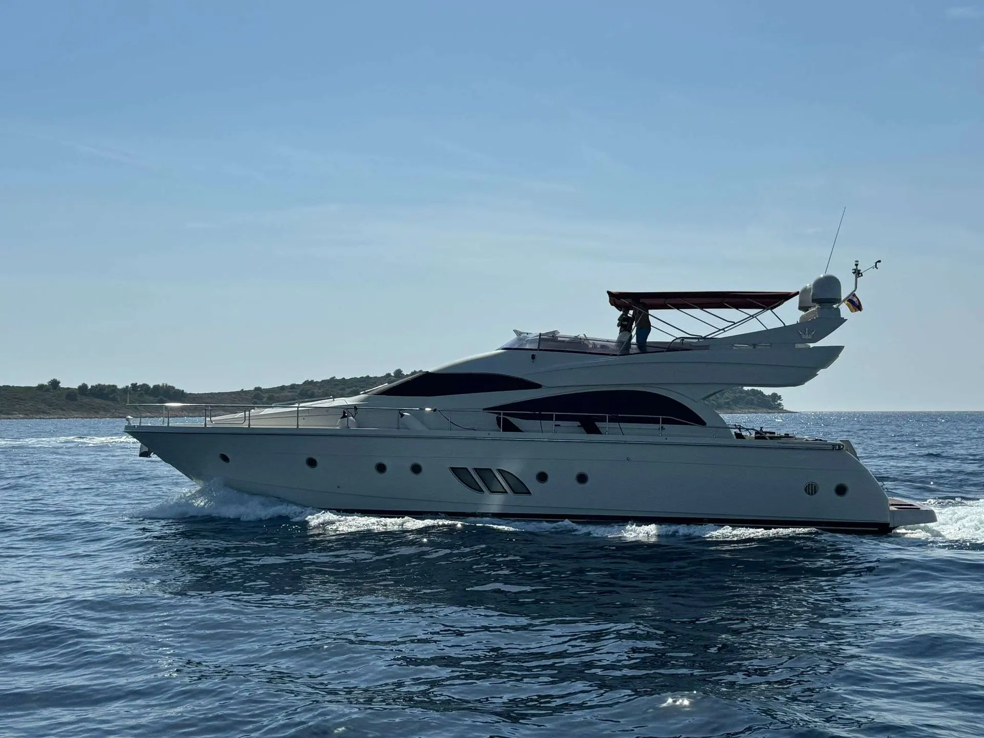 Dominator 62 — Yacht à moteur vu de profil, naviguant en mer près d’une côte.