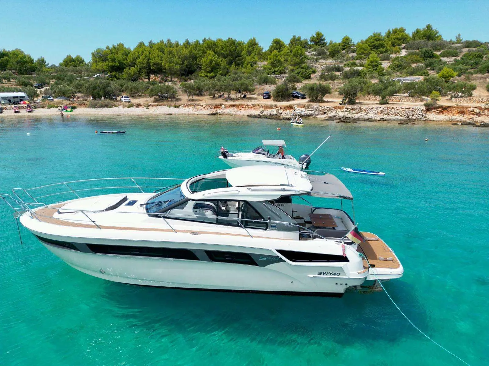 Bavaria Sport 40 — Bateau à moteur blanc vu de trois quarts dans une baie aux eaux turquoise.