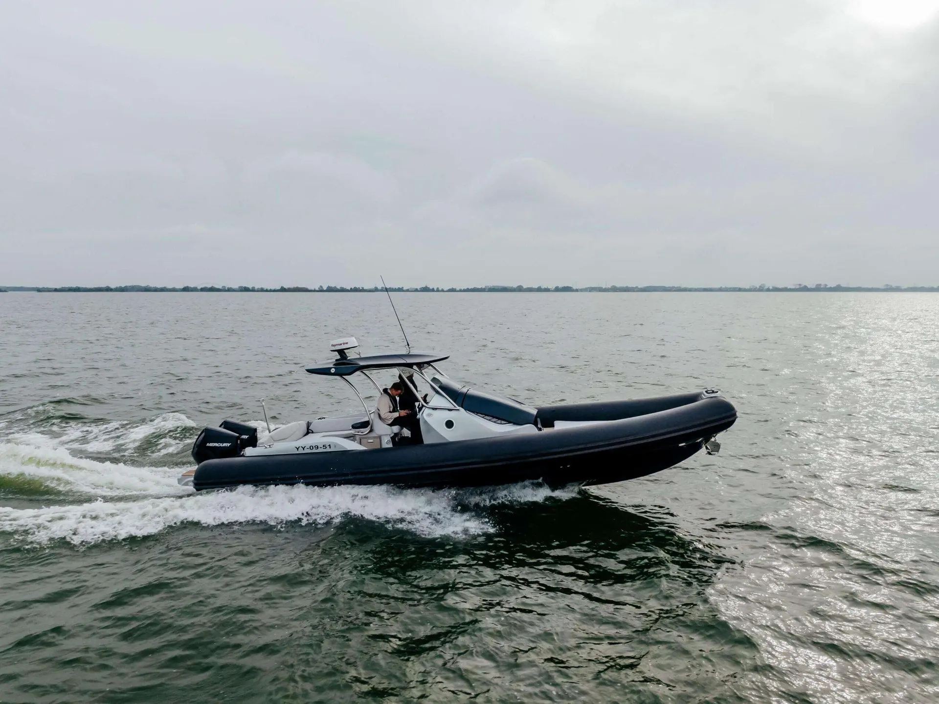 Sacs Strider 10 — Bateau semi-rigide noir naviguant sur un plan d’eau, avec une personne à bord.