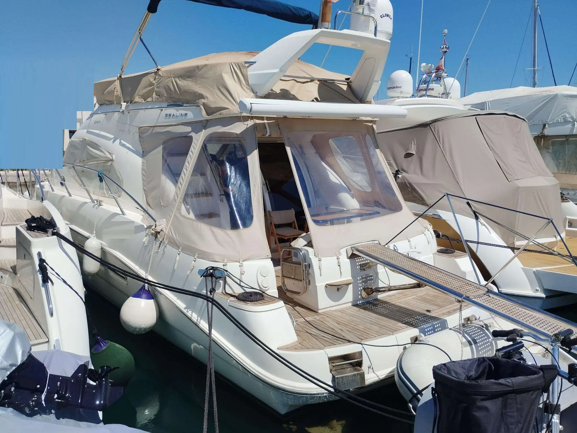 Sealine F 42/5 — Bateau à moteur amarré, vu de trois quarts depuis l’avant dans une marina.