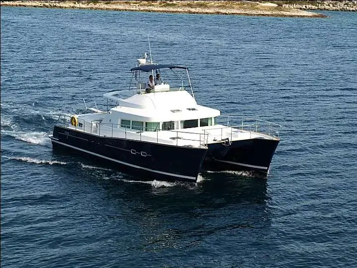Lagoon Power 43 — Catamaran à moteur blanc et bleu naviguant près d’une côte rocheuse