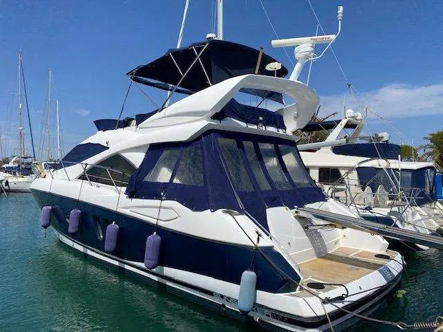 Sunseeker Manhattan 50 — Bateau à moteur blanc et bleu amarré dans une marina, vu de trois quarts arrière.