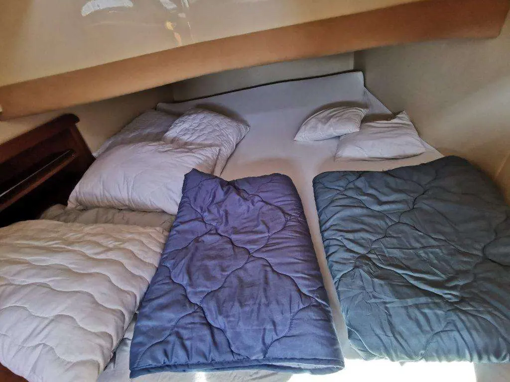 Sealine SC 39 — Couchette intérieure avec lit double et couvertures disposées à bord.