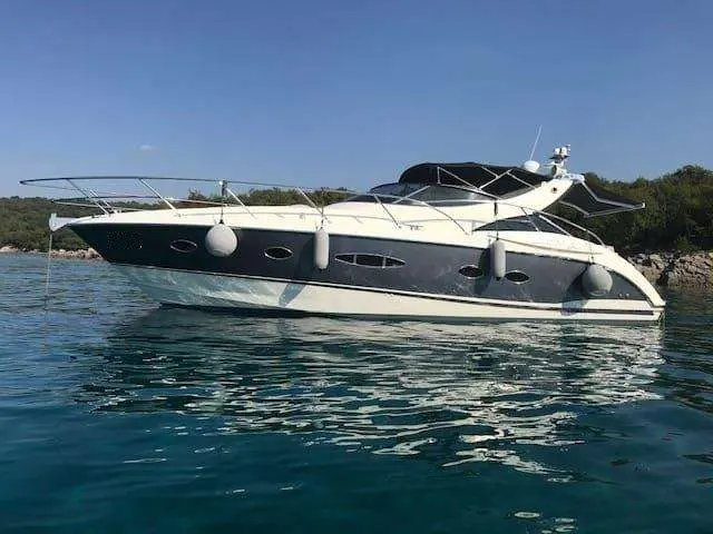 Azimut Atlantis 39 — Bateau à moteur vu de profil sur une eau calme, près d’une côte rocheuse.