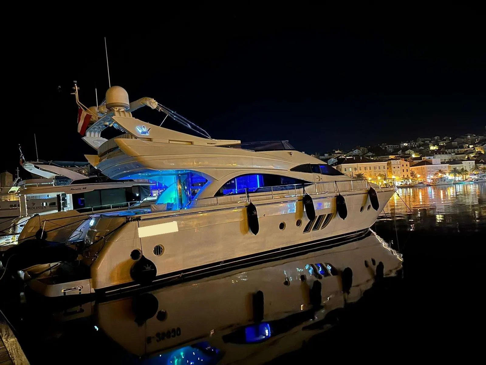 Dominator 62 — Vedette blanche amarrée de nuit dans un port éclairé.