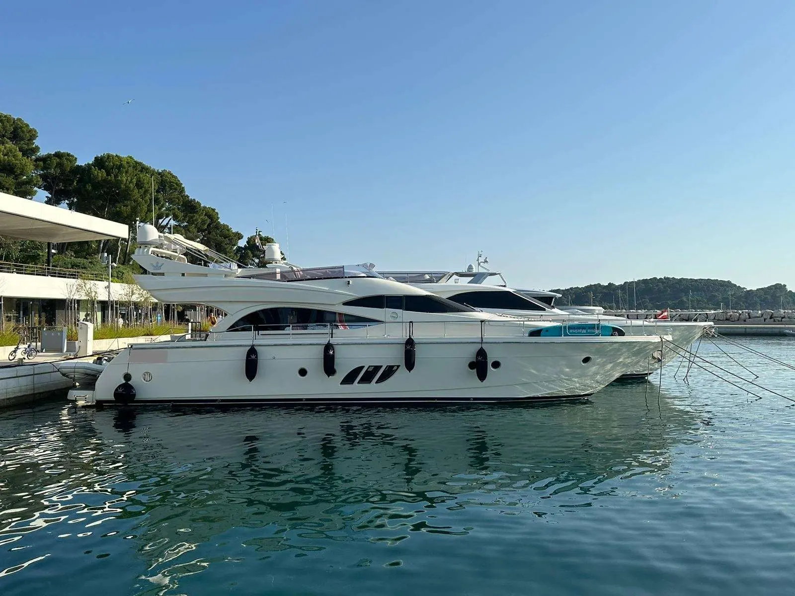 Dominator 62 — Yacht à moteur blanc amarré dans une marina, vu de profil par tribord.