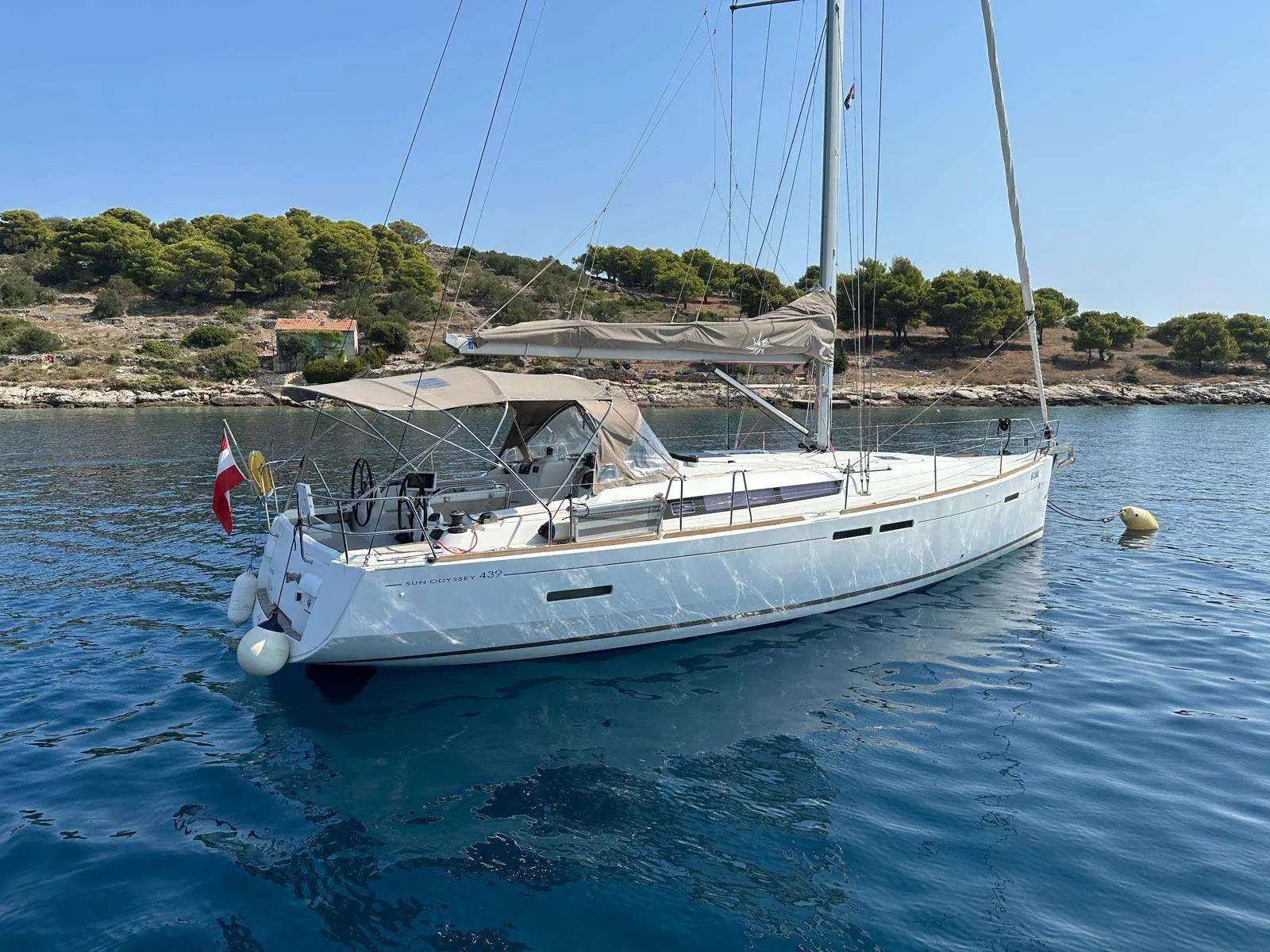 Jeanneau Sun Odyssey 439 — Voilier blanc vu de trois quarts au mouillage, avec son gréement et ses voiles ferlées.