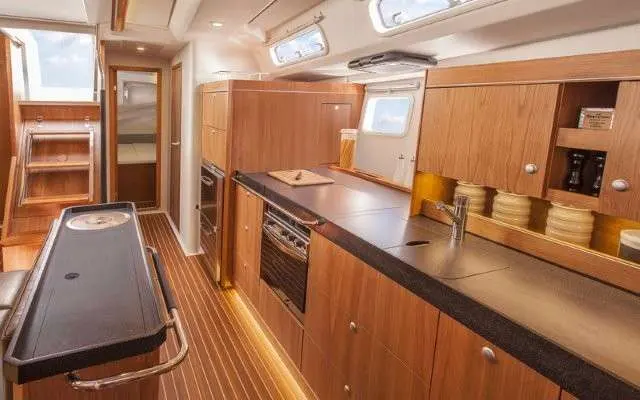 Hanse 505 — Cuisine intérieure en bois avec plan de travail, évier et appareils intégrés.