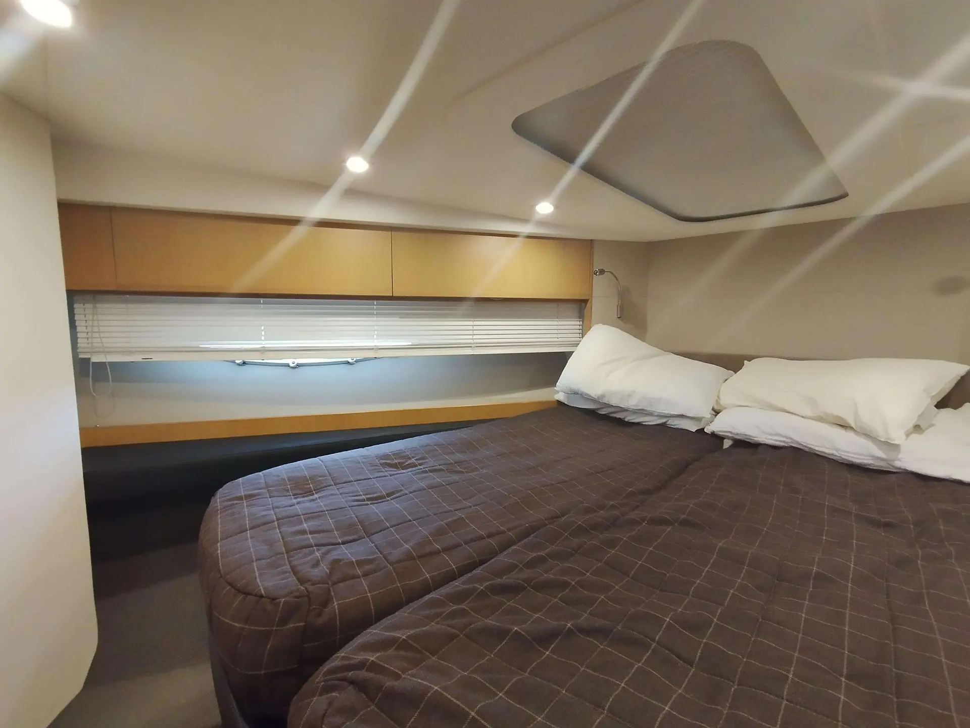 Princess V52 — Cabine intérieure avec lit double, hublot à stores et éclairage encastré.