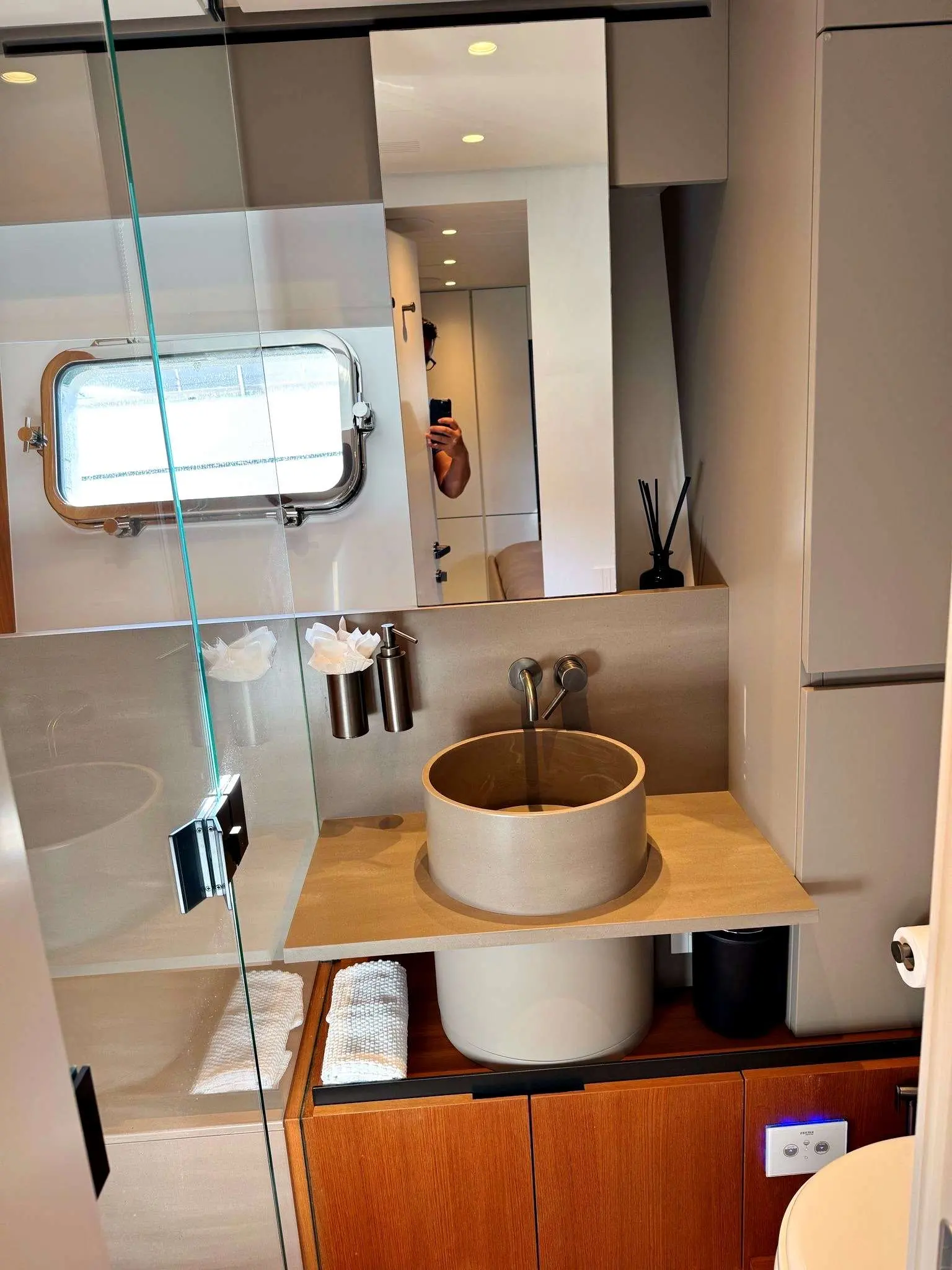 Bluegame BGX 70 — Salle de bains avec vasque ronde, miroir, douche vitrée et rangements en bois.