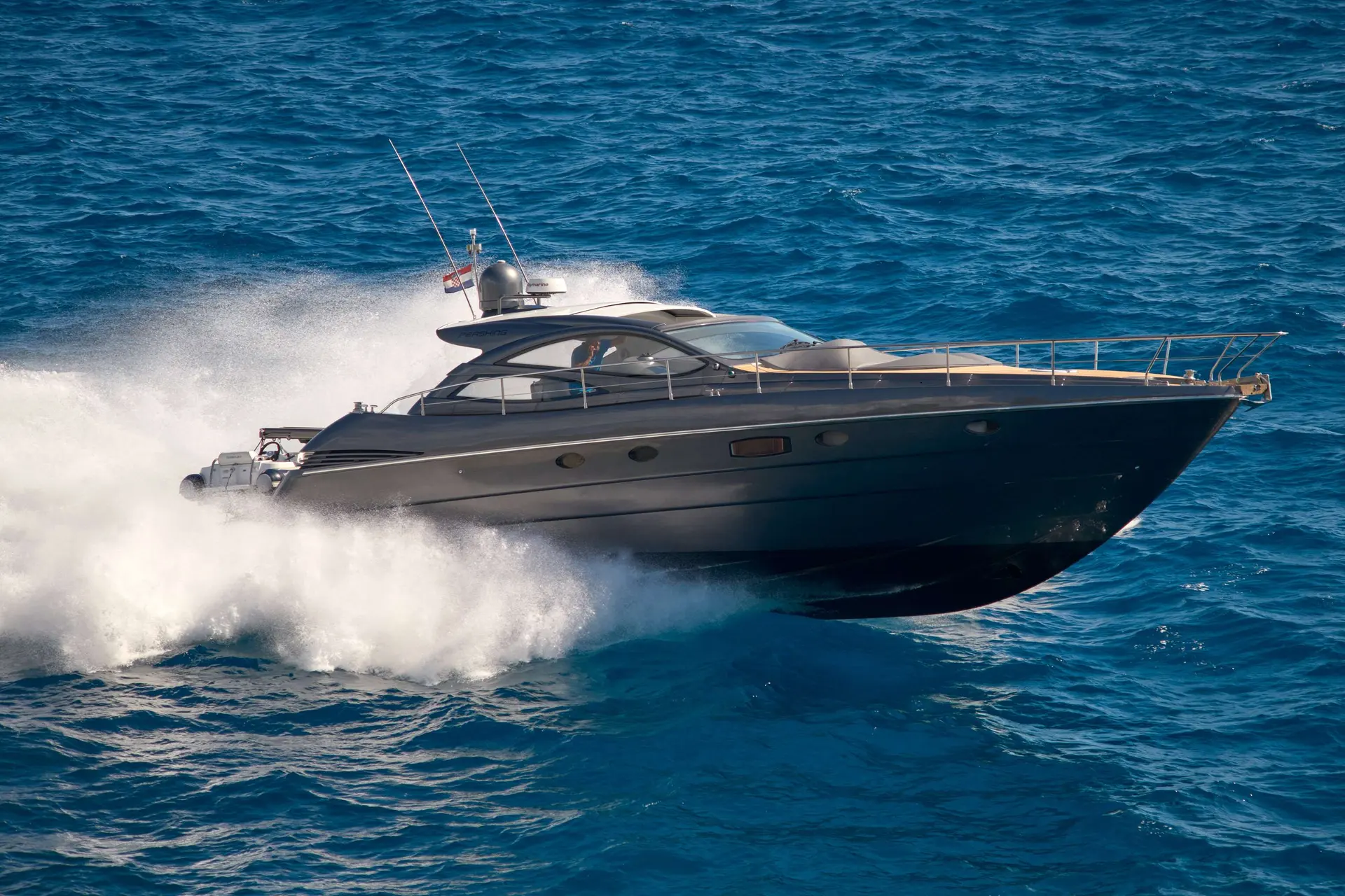 Pershing 50 — Bateau à moteur gris naviguant rapidement sur une mer bleue, vu de trois quarts.