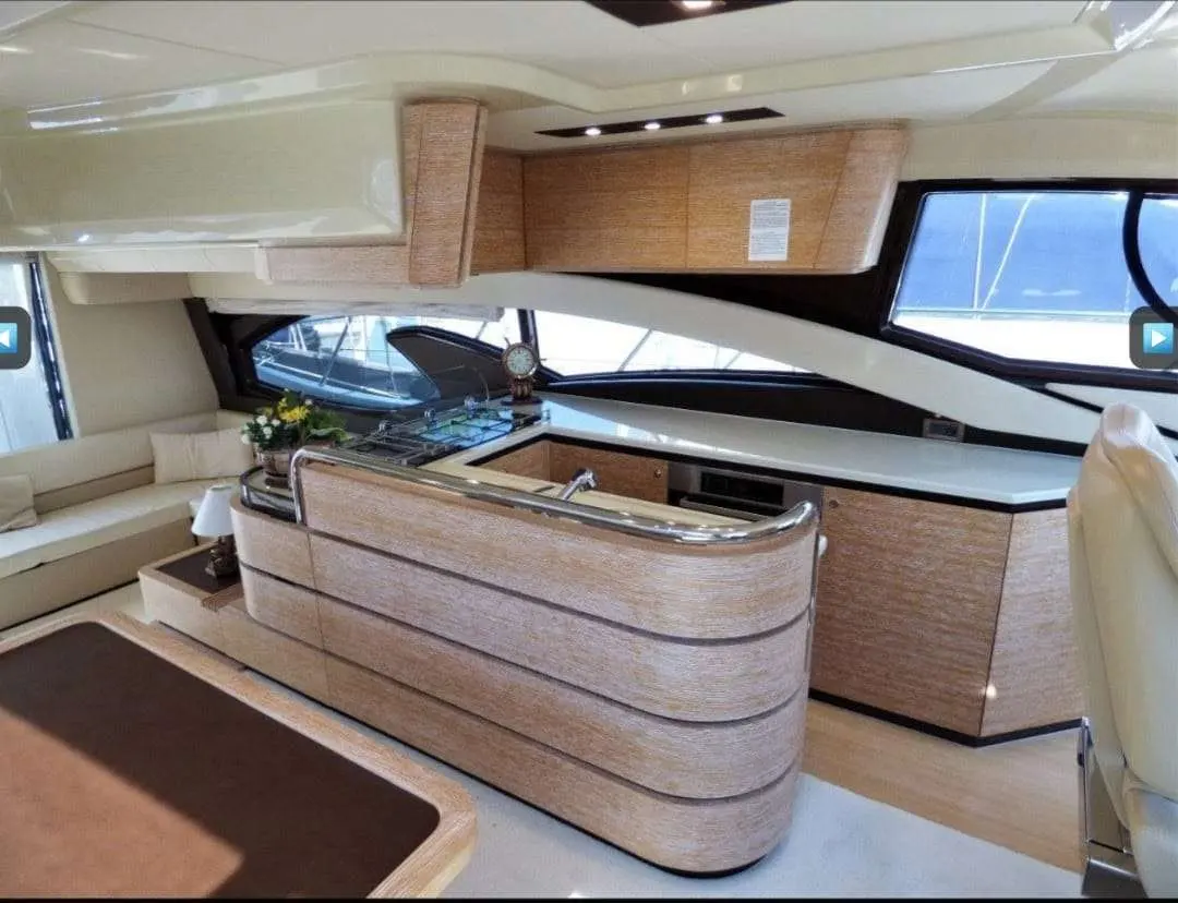 Azimut 60 Fly — Vue intérieure du salon avec cuisine intégrée et mobilier en bois.