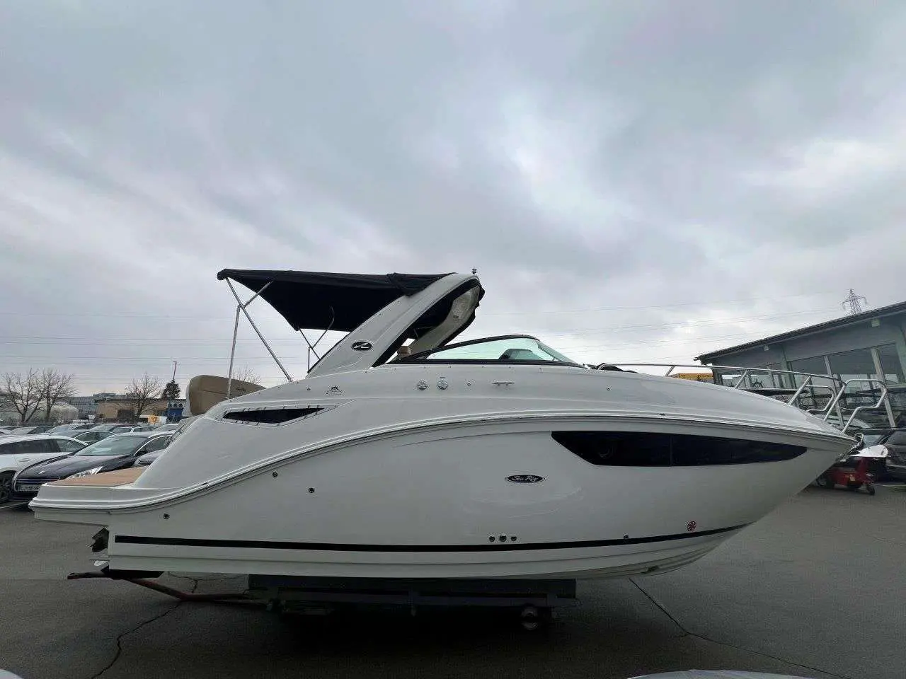 Sea Ray Sundancer 265 — Bateau à moteur blanc présenté de profil sur sa remorque, dans un parc nautique.