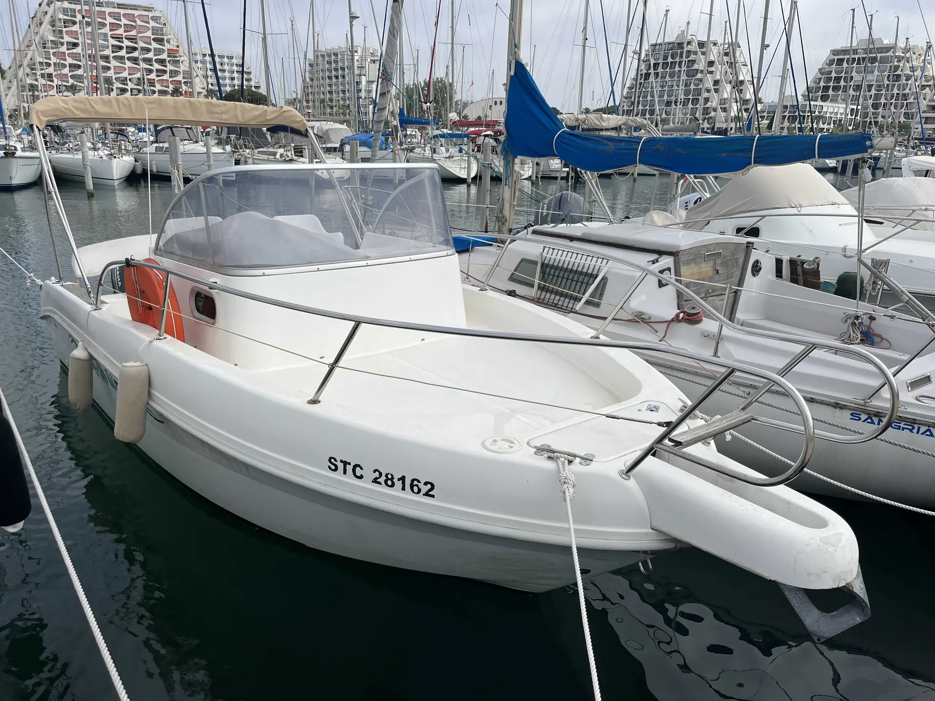 Capelli Cap 23 Open — Bateau à moteur blanc amarré dans un port de plaisance, vu de trois quarts.