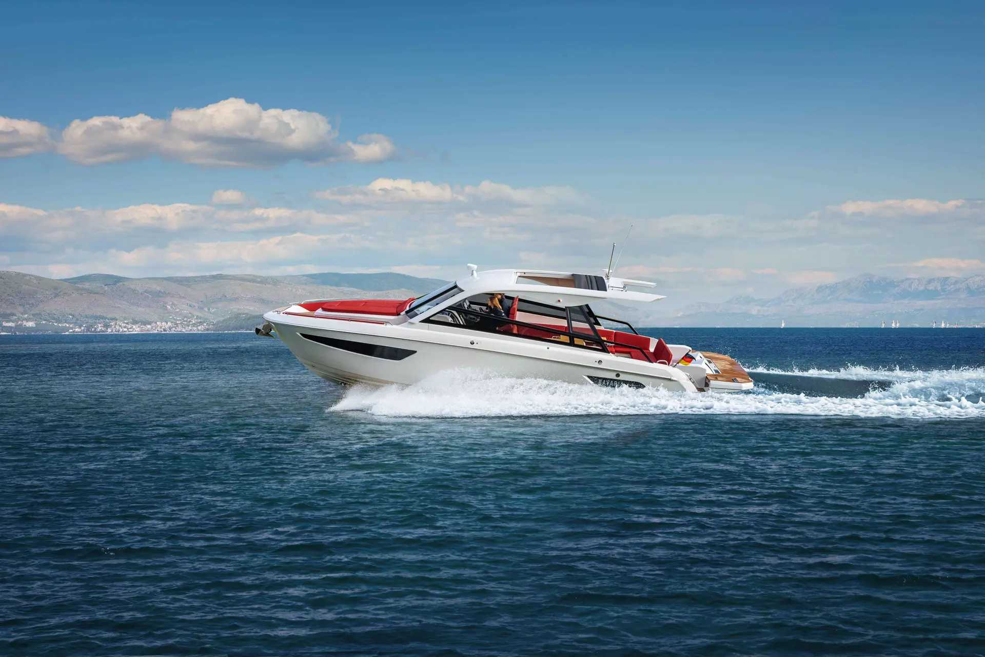 Bavaria Vida 33 Coupe — Bateau à moteur blanc naviguant à vive allure devant un paysage côtier.
