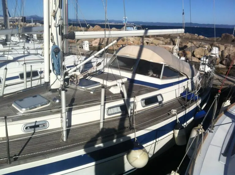 Hallberg Rassy 36 — Voilier amarré dans un port, vu de trois quarts depuis un bateau voisin.