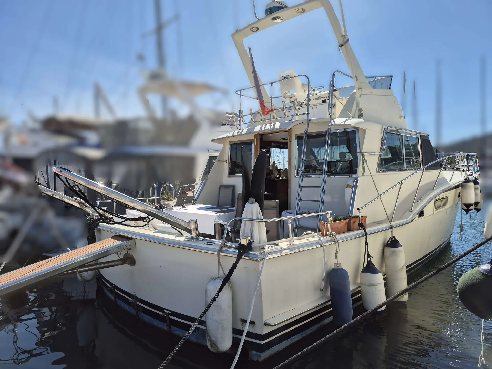 Hatteras 46 Convertible — Bateau à moteur amarré dans une marina, vu de trois quarts arrière.